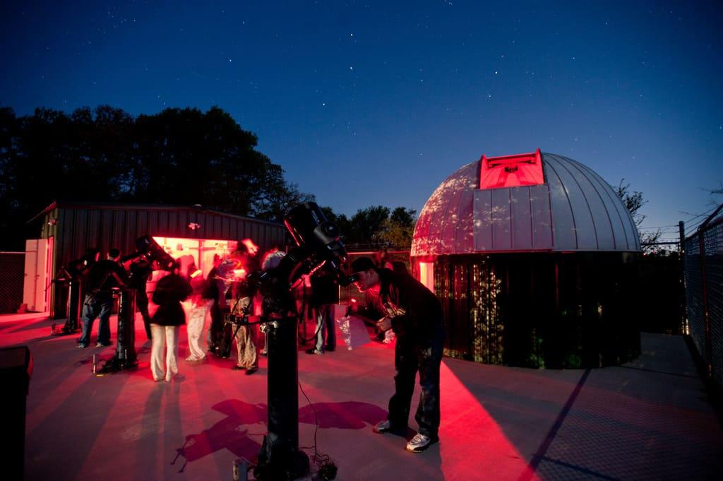 Students viewing stars with giant telescope.