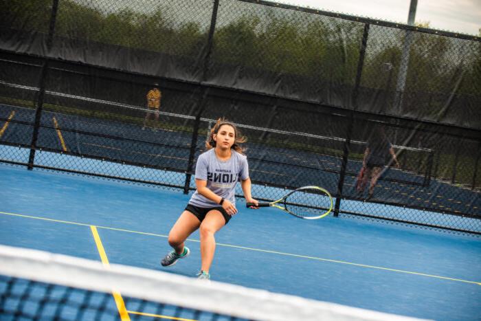A student playing tennis.