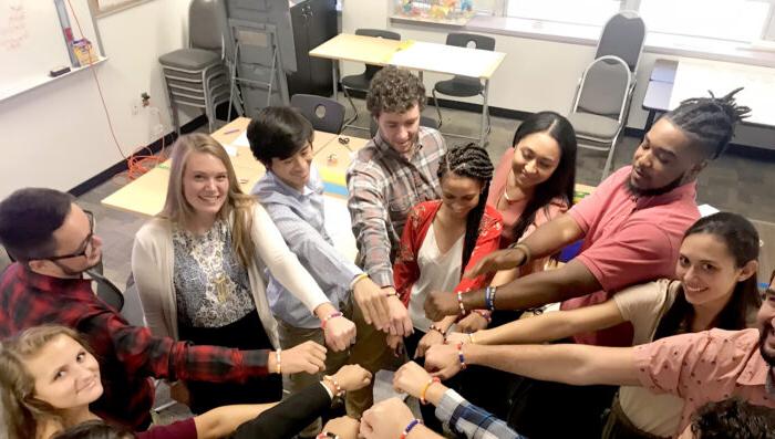 A group of student in a circle touching hands.