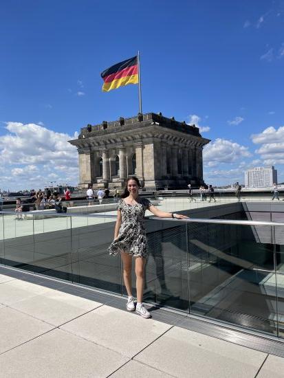 A female student in front of a building with a Germany flag.